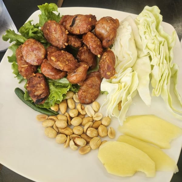 A plate of Sapp Coffee Shop's Thai sausage with lettuce, cabbage, peanuts, and sliced ginger.